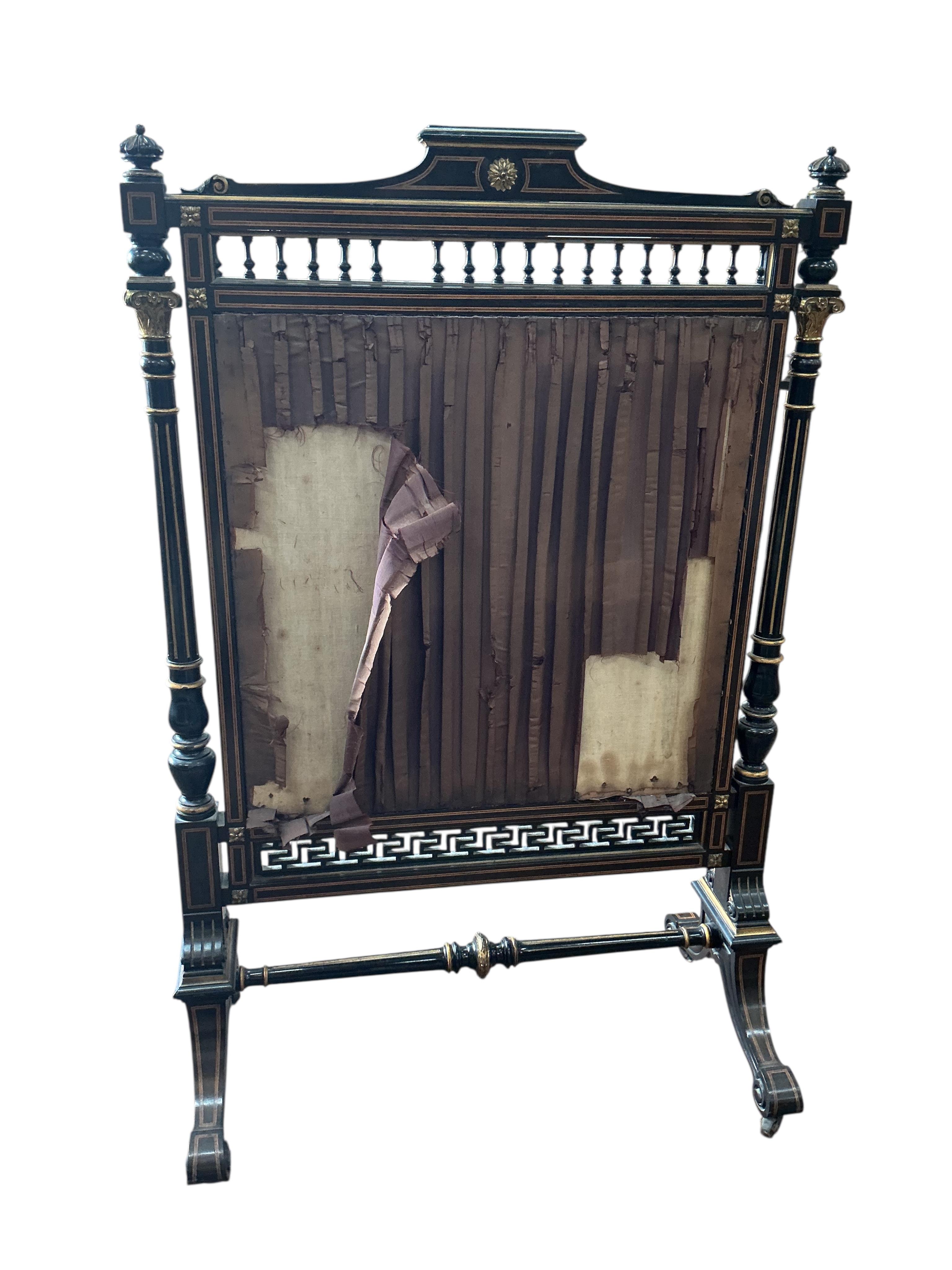 A late Victorian gilt metal mounted part ebonised bird's eye maple firescreen inset circular woolwork floral banner, width 79cm, height 122cm